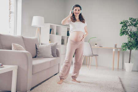 Full length photo of young curly hair cheerful pregnant woman have fun enjoy listen music headphones...