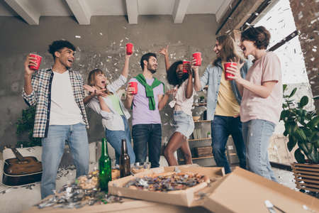 Photo of excited happy group of friends drink red cup toast celebrate party dormitory indoors inside...