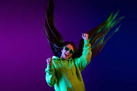 Photo of cheerful crazy happy young woman raise fists fly hair long winner isolated on gradient purple color backgroundの写真素材