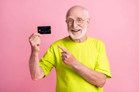 Photo of old happy cheerful smiling grandfather wear lime t-shirt point finger at credit card...