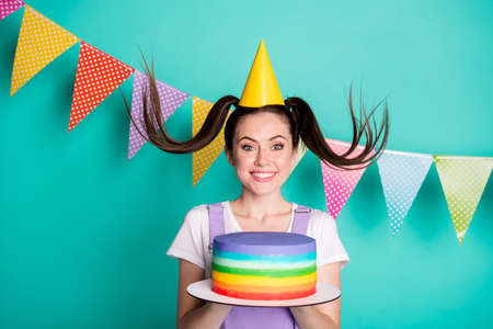 Photo portrait of funny birthday girl wearing cap tails keeping rainbow cake smiling isolated on vivid teal color backgroundの写真素材