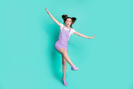 Full length body size photo of careless playful girl pretending plane with wings isolated on vibrant...