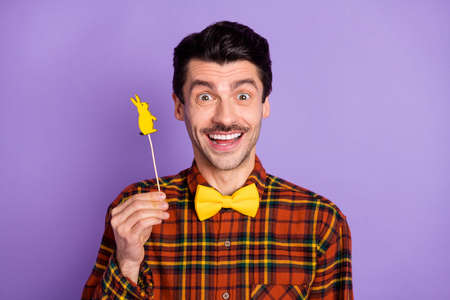 Photo of crazy guy hold rabbit shape candy stick look camera wear bow tie checkered shirt isolated...