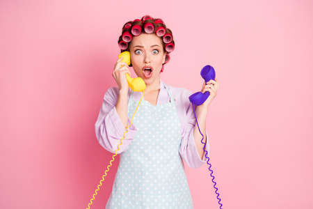 Portrait of attractive person hands hold two old phones open mouth isolated on pink color backgroundの写真素材