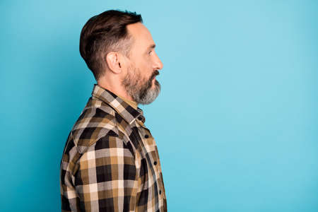 Profile photo of bearded self-assured man look empty space wear checkered shirt isolated blue backgroundの写真素材