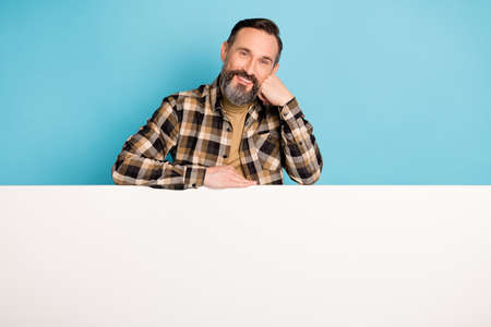 Photo of man fist cheek lay white placard empty space toothy smile wear checkered shirt isolated...