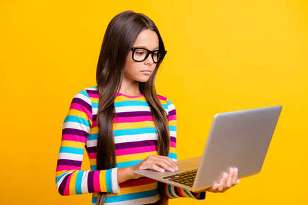 Photo portrait of smart schoolgirl wearing spectacles working with laptop reading concentrated...