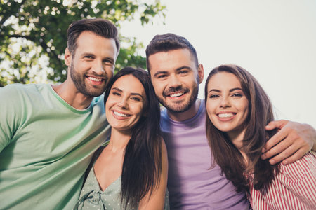Low angle view photo of four happy friends men and women hug beaming smile good mood outside in outdoorsの写真素材