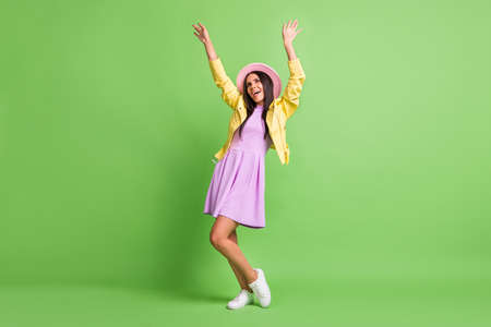 Photo of pretty lady raise hands dance wear yellow jacket violet dress pink cap sneakers isolated...