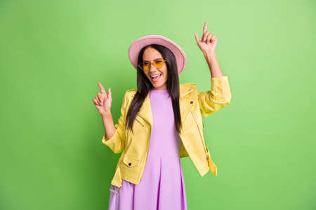 Photo portrait of woman wearing sunglass pink hat dancing at party laughing isolated on vibrant green color backgroundの写真素材