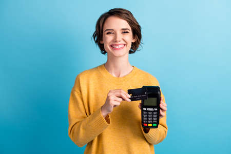 Photo of young nice cool lady hold debit card terminal courier offer cashless pay wear yellow...
