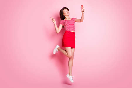 Full size photo of young beautiful smiling cheerful positive showing v-sign take selfie jump...