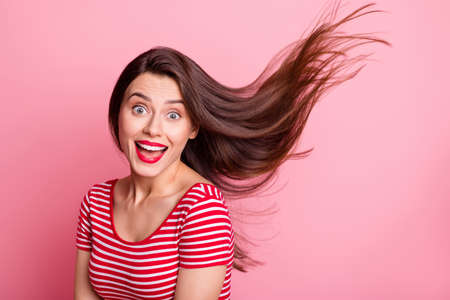 Portrait of young beautiful excited smiling good mood girl open mouth flying hair isolated on pink color backgroundの写真素材