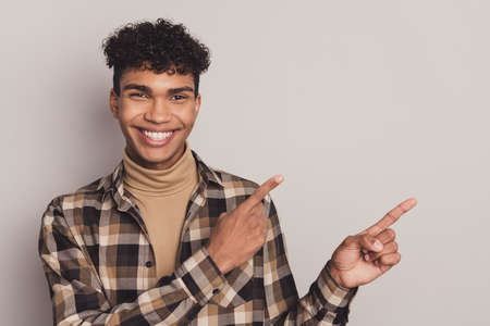 Photo of guy direct forefingers empty space advising wear checkered shirt rollneck isolated grey...