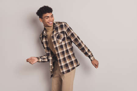 Photo of funky happy dark skin young man dance empty space music lover isolated on grey color...