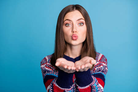 Portrait of attractive affectionate brown-haired girl ending you air kiss isolated over vibrant blue...