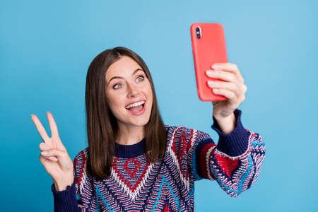 Photo portrait girl using smartphone taking selfie showing v-sign gesture smiling isolated bright...