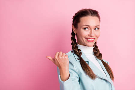 Profile side photo of young cheerful girl look point thumb empty space ad promo advice choice isolated over pink color backgroundの写真素材