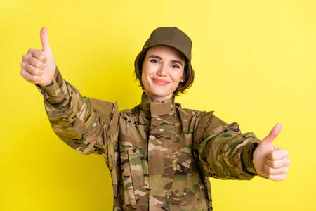 Photo of charming positive girl show two arms thumbs up smile have good mood isolated on yellow color backgroundの写真素材