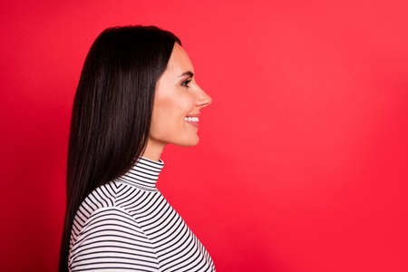 Profile side photo of young happy cheerful smiling girl look copyspace wear striped turtleneck isolated on red color backgroundの写真素材