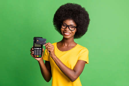 Photo of young cheerful beautiful afro girl using credit card on terminal cashless payment isolated...