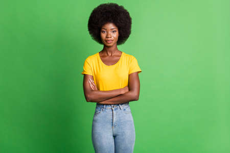 Photo of young serious beautiful charming good looking afro girl with folded hands isolated on green color backgroundの写真素材