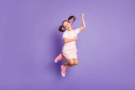 Full size photo of charming happy little girl jump up air weekend positive isolated on purple color backgroundの写真素材