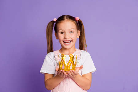 Photo of happy amazed little girl hold hands crown wear white t-shirt isolated on purple color backgroundの写真素材