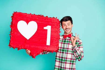 Photo of positive guy hold big like pinata beaming smile wear checkered shirt bowtie isolated blue...