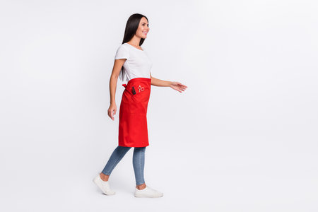 Full size profile side photo of young beautiful smiling hairdresser look copyspace go walk isolated on grey color backgroundの写真素材