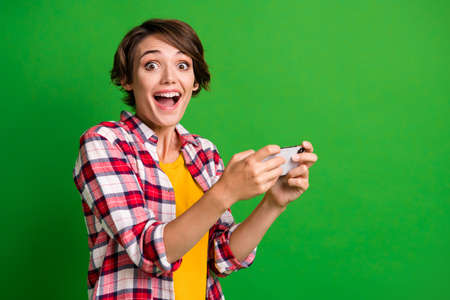 Photo of attractive positive lady games player impressed open mouth plaid shirt isolated on green...