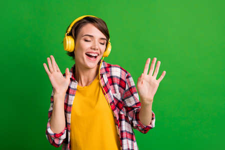 Photo of funky pretty short hairstyle lady listen music closed eyes dancing wear yellow cloth isolated over vivid green color backgroundの写真素材
