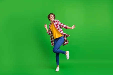 Full size photo of pretty cute lady dancing hands fists wear jeans shirt sneakers isolated on green color backgroundの写真素材