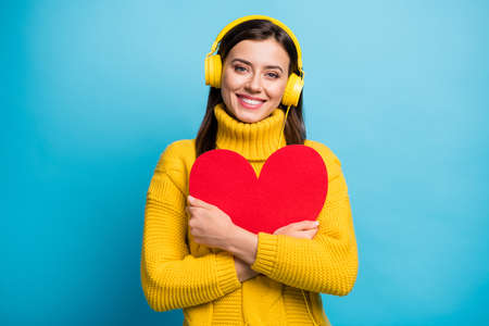 Close-up portrait of pretty cheerful girl embracing red heart shape listening single isolated over bright blue color backgroundの写真素材