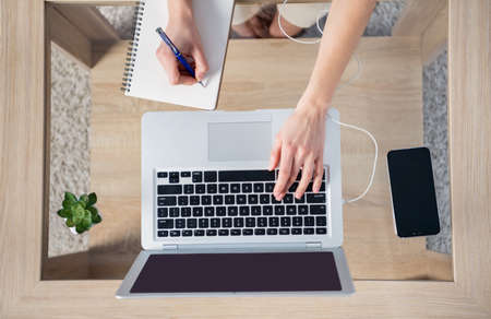 High angle view photo of businesswoman remote working at home house typing laptop writing in...