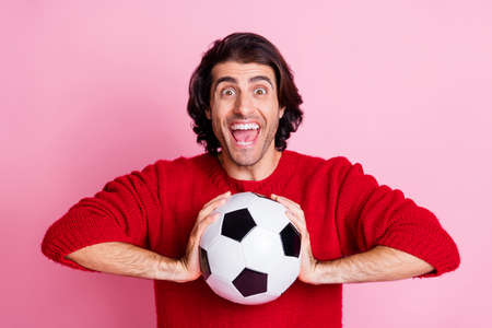 Photo portrait of screaming guy holding football in two hands isolated on pastel pink colored backgroundの写真素材