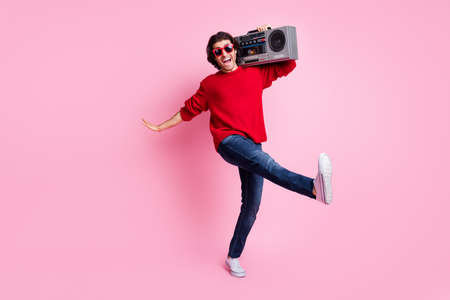Photo portrait of cool guy dancing kicking standing on one leg holding boombox wearing sunglasses isolated on pastel pink colored backgroundの写真素材