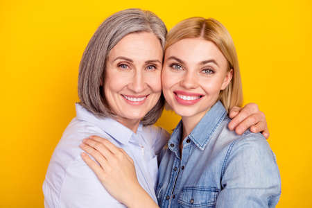 Photo portrait of happy granddaughter embracing her smiling cheerful granny isolated vivid yellow color backgroundの写真素材