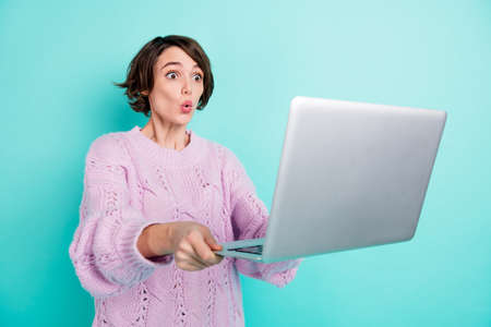 Photo of impressed funny young lady dressed purple pullover holding modern gadget isolated teal...
