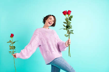 Photo of funny adorable young woman wear violet sweater holding red roses isolated turquoise color backgroundの写真素材