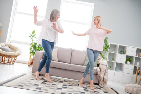 Full length photo of attractive active old woman and young lady dance wear casual clothes indoors inside house homeの写真素材