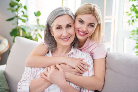 Photo of happy nice mother and daughter hug smile good mood free time weekend indoors inside house homeの写真素材