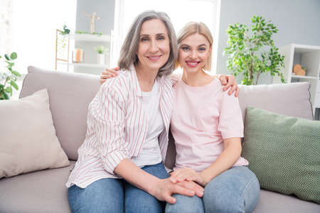 Photo of happy positive cheerful women old lady young girl sit sofa smile hug family indoors inside house homeの写真素材
