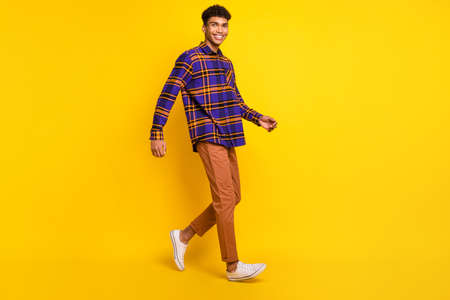 Full size profile photo of positive dark skin person walking toothy smile isolated on yellow color...