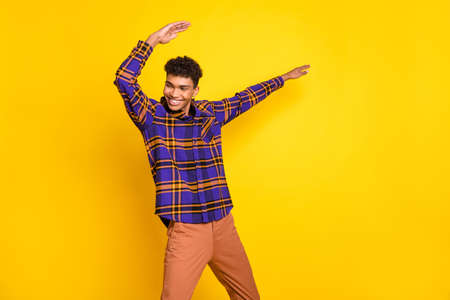 Photo of young excited man happy positive smile have fun enjoy dance look empty space isolated over yellow color backgroundの写真素材
