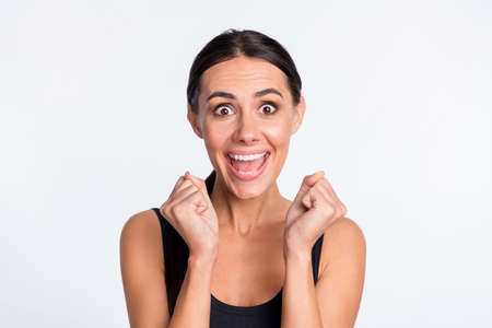 Photo of crazy happy young woman astonished amazed winner raise fists isolated on grey color backgroundの写真素材