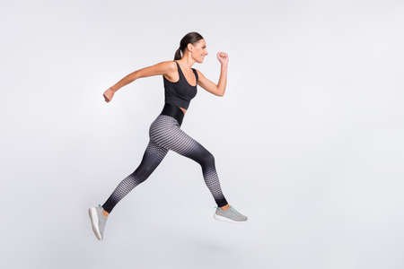 Full size profile side photo of brown haired ponytail lady jump up run empty space isolated on grey...
