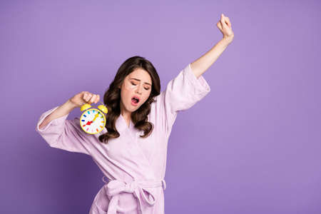 Photo of young sleepy woman yawn use under eye patch hold clock isolated over purple color...