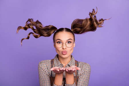 Portrait of lovely charming lady hands palms sending air kiss you hair flying isolated on purple...