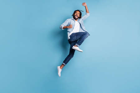 Full length body size view of nice cool lucky active cheerful guy jumping having fun isolated over bright blue color backgroundの写真素材